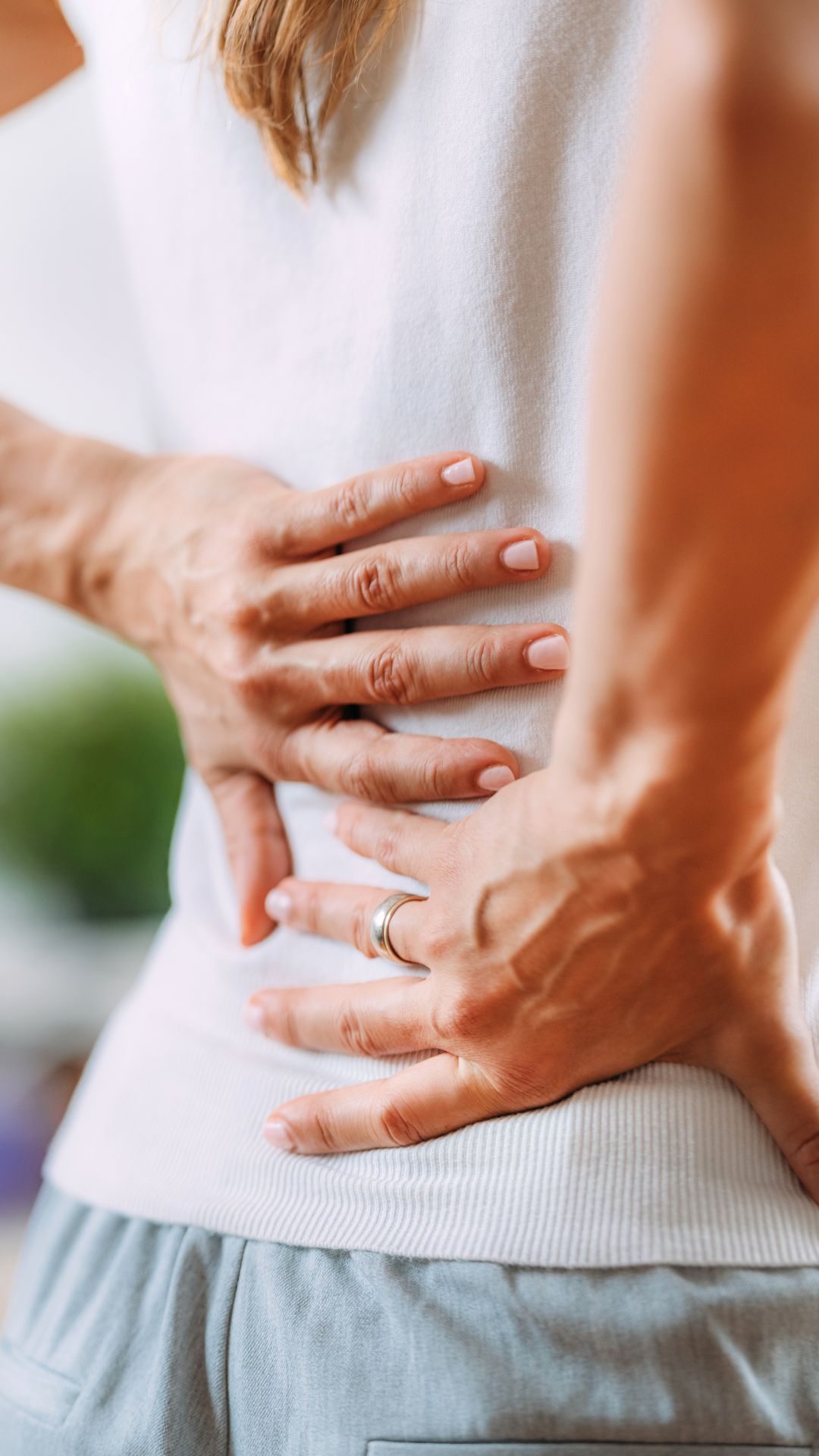 Person holding their lower back in pain