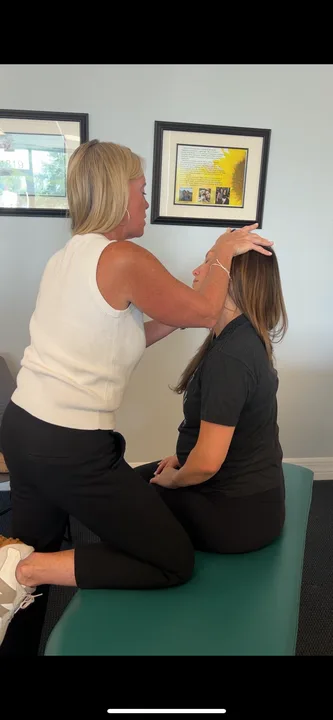 Dr. Kim Raby working on a seated patient's neck muscles
